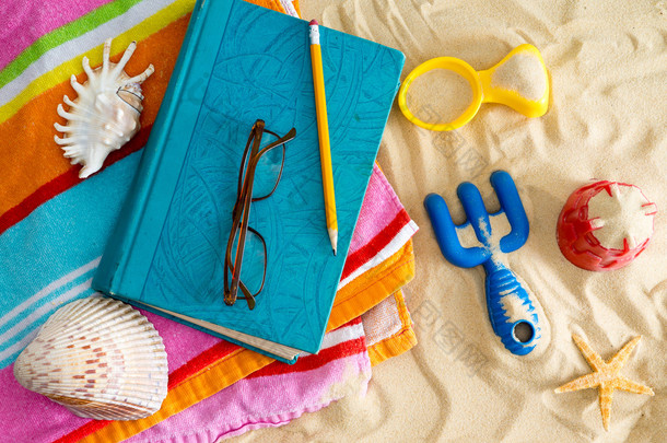 上一条海滩浴巾的书本和阅读眼镜