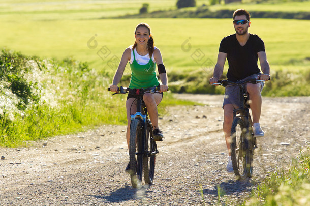 快乐在乡下骑一辆自行车上的年轻夫妇