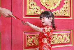 女人手给的红包礼金为可爱的小女孩，在泰国曼谷的中国庙宇。中国农历新年的概念.