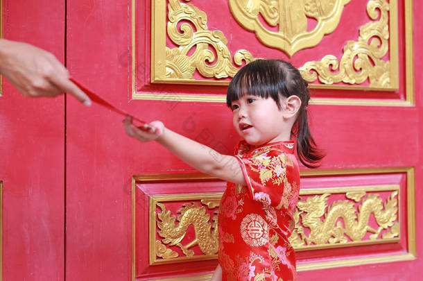 女人手给的红包礼金为可爱的小女孩，在泰国曼谷的中国庙宇。中国农历新年的概念.