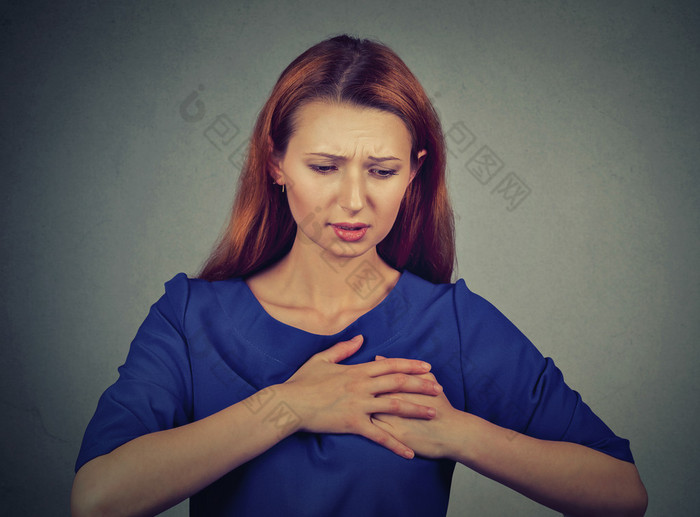 young woman with breast pain touching chest isolated on gray wall background