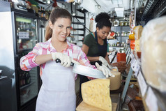 快乐的女工切片奶酪用刀在店里