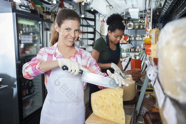 快乐的女工切片奶酪用刀在店里