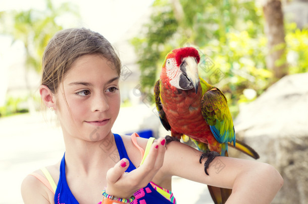可爱的小女孩和一只鹦鹉一起玩