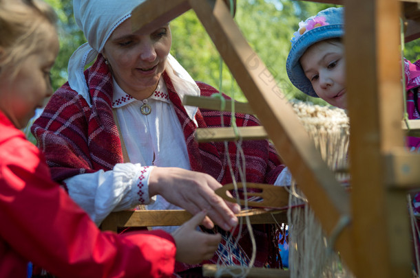 微笑在波罗的海区域显示在织布机上工作的儿童民族服装的女高管