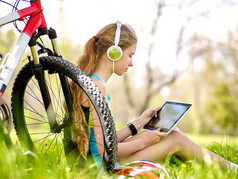 自行车骑自行车在 pc 平板电脑附近自行车戴耳机手表的女孩.