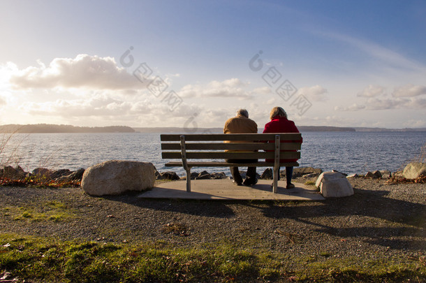 在公园的长椅上，面对一个湖上一起放松对老年夫妇