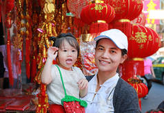 中国农历新年春节在唐人街在曼谷，泰国亚洲女人和她的女儿在中国服饰对传统中国红装饰是很受欢迎.