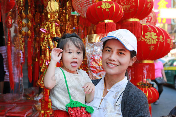 中国农历新年春节在唐人街在曼谷，泰国亚洲女人和她的女儿在中国服饰对传统中国红装饰是很受欢迎.