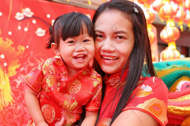 春节快乐，可爱的亚洲女孩微笑和拥抱她的孩子在传统中国服饰