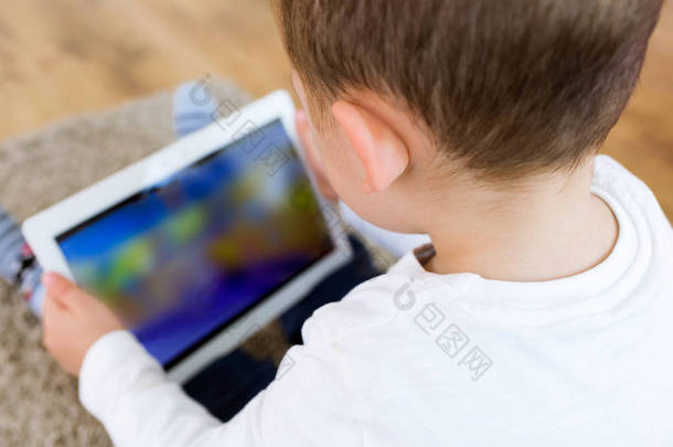 美丽的小男孩在家里使用他数字平板电脑.