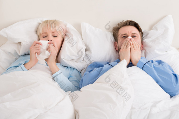 对夫妇躺在床上吹他们的鼻子