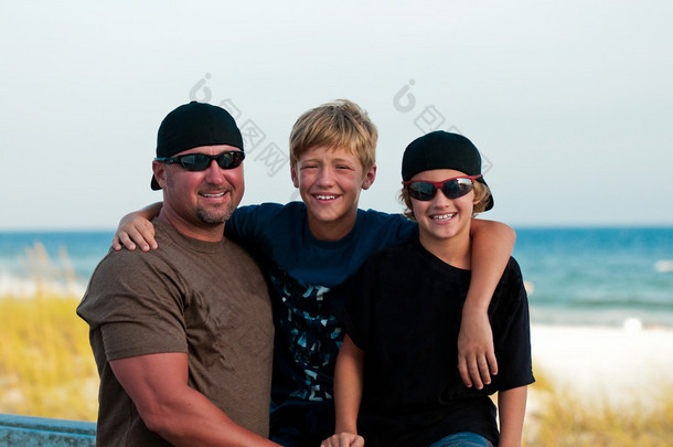父亲和两个儿子在海滩的肖像.