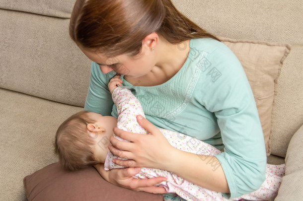 年轻的妈妈<strong>母乳</strong>喂养她的孩子在家里