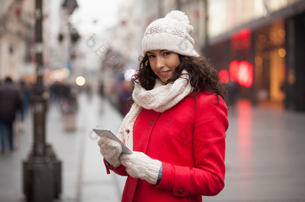 智能手机在汉红色外套和<strong>羊毛</strong>帽和手套的女人