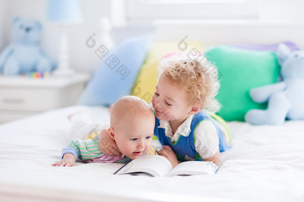 Little brothers reading a book in bed