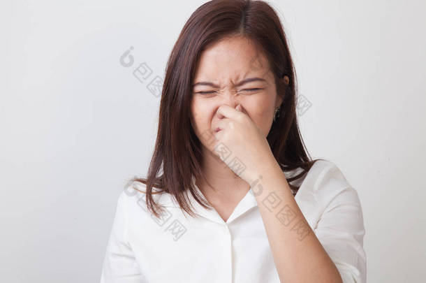 年轻的亚洲女子，捧着她的鼻子因为难闻的气味.