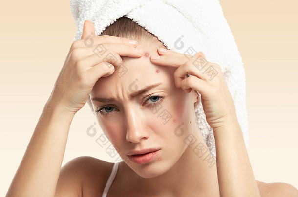 woman squeezing pimple on forehead