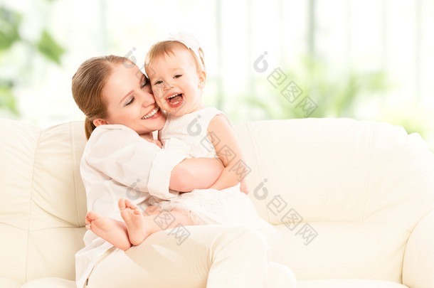 幸福的家庭。母亲和婴儿的女儿起坐在沙发上