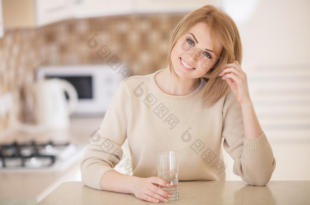 美丽的女人，在厨房与一杯水