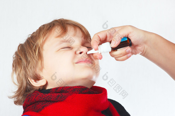 小男孩在鼻子中使用医疗的鼻喷雾<strong>剂</strong>