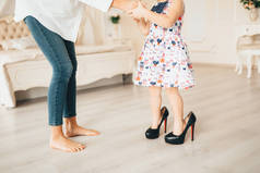 一个小女孩在她母亲的鞋子。一个孩子穿着她的母亲