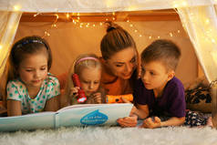 小女孩和逗人喜爱的孩子读书在小屋在家