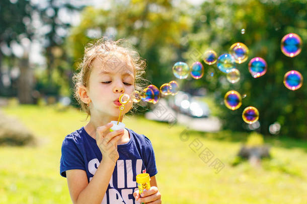 <strong>一个</strong>小女孩在夏天公园吹肥皂泡泡。背景色调 instagram 筛选器.