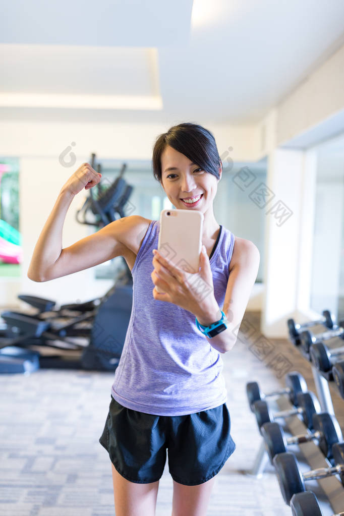 智能手机以镜子自拍照在健身房中的女人