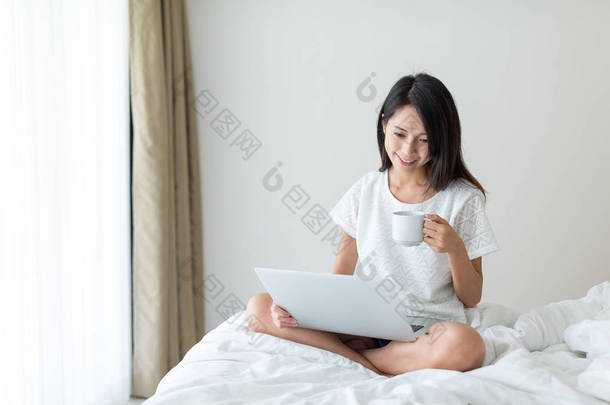在便携式计算机上工作，喝咖啡的女人