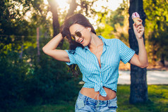 young beautiful short blue hair hipster woman with headphones music in the park. ice cream