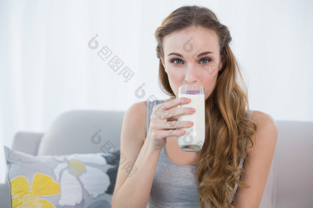 幸福的年轻女<strong>人</strong>，<strong>坐</strong>在<strong>沙发上</strong>喝牛奶