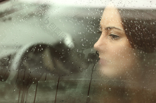 Sad woman looking through a car window