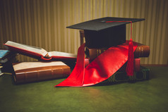 色调红丝带和毕业帽经典桌上的照片