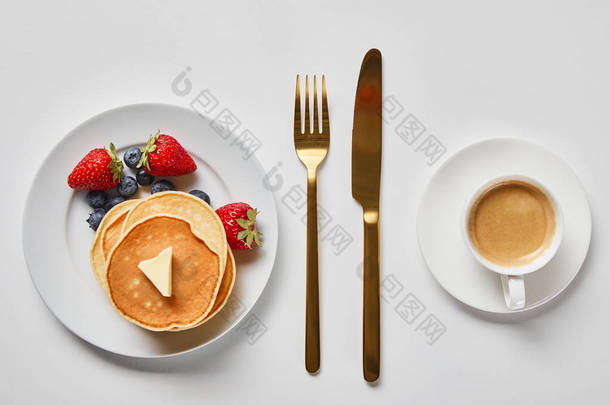 美味的早餐，在金餐具附近享用煎饼、浆果和咖啡