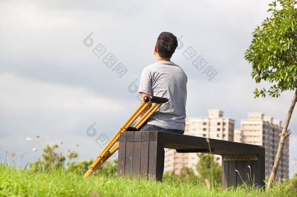 受伤的男子坐在一条长凳上的<strong>拐杖</strong>