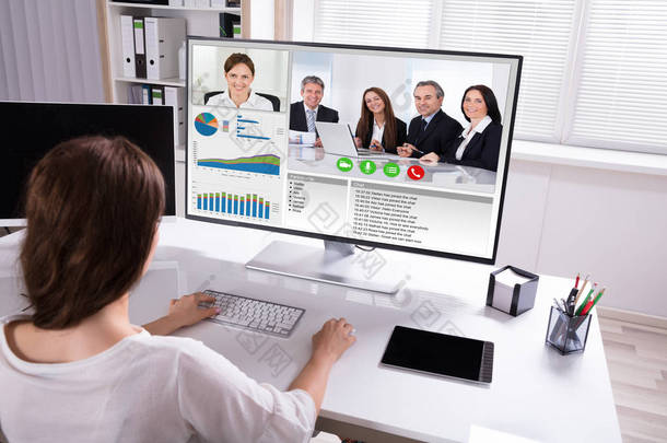 后视图的女实业家视频会议与同事在计算机上的<strong>工作</strong>场所