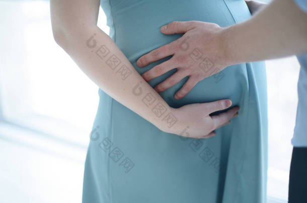 怀孕的女人抱着她的肚子和未来的父亲