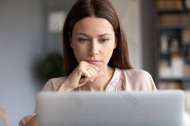 亲密体贴的女人摸着下巴，看着手提电脑屏幕