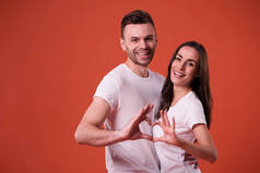 快乐美丽的年轻夫妇在爱情有一个乐趣, 在白色的 t恤, 而摆姿势橙色的背景