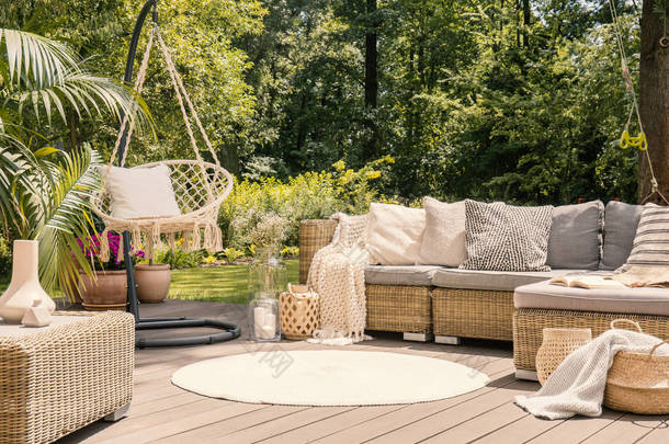 一个大阳台与舒适的休闲沙发与垫子, 一张桌子和一个字符串摆动在一个绿色的花园, 在阳光明媚的假期.