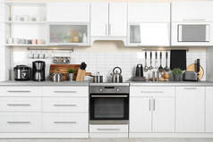 厨房柜台上有不同的电器、干净的餐具和餐具