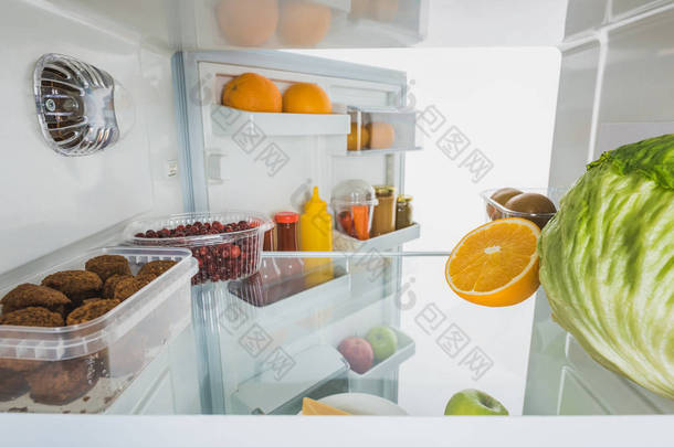 冰箱中新鲜水果、<strong>切</strong>片和卷心菜，敞开的门与白色隔离