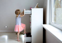 小女孩爬上现代的高级梳妆台家具,危险的梳妆台俯冲在概念之上.儿童的家庭危险。分阶段照片.