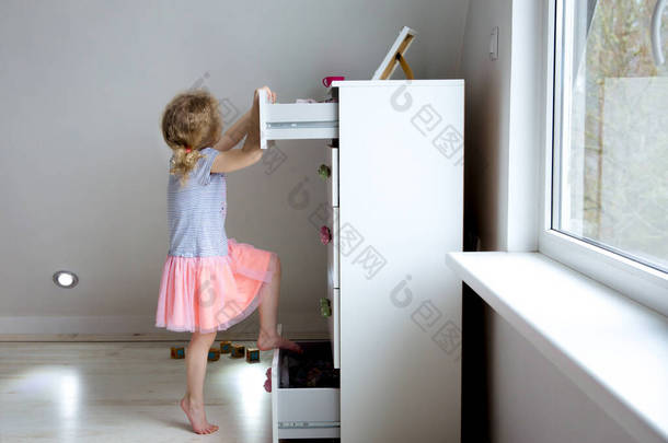 小女孩爬上现代的<strong>高级</strong>梳妆台家具,危险的梳妆台俯冲在概念之上.儿童的家庭危险。分阶段照片.
