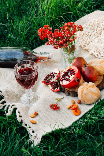 公园里的野餐。石榴、面包、梨、花、酒和玻璃杯图片