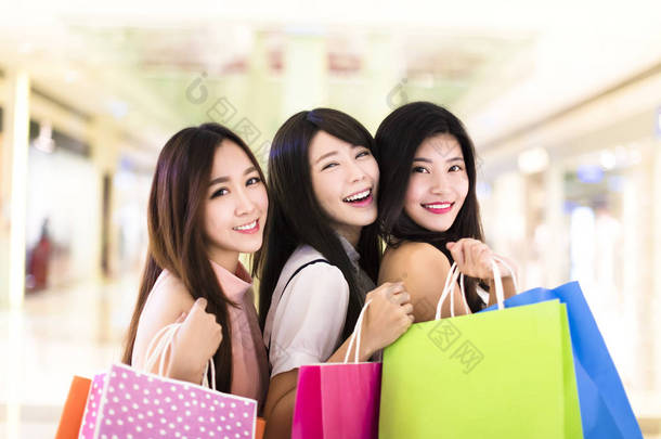 幸福的女人组提着购物袋行走在购物中心