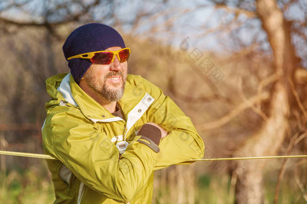 男人调整前疯狂走扁带技巧，slacklin 在自然公园走路走扁带设备的特写肖像