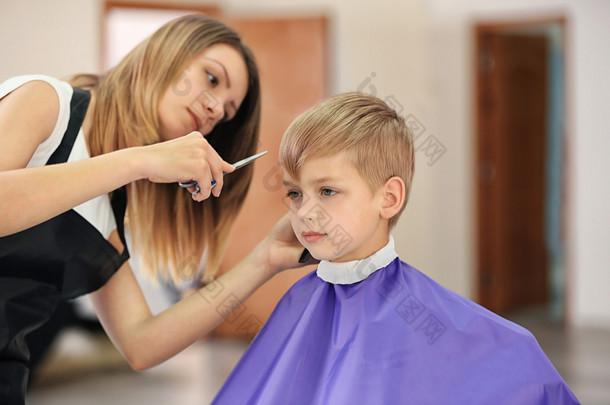 理发师在模糊的背景下给孩子做发型