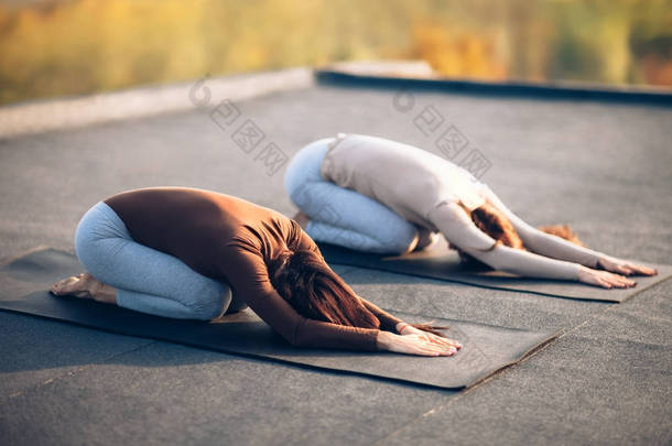  妇女做瑜伽体式孩子的姿势 